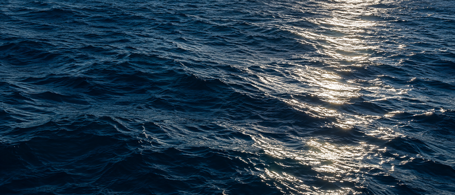 Sunlight traces a silver path across deep blue ocean currents